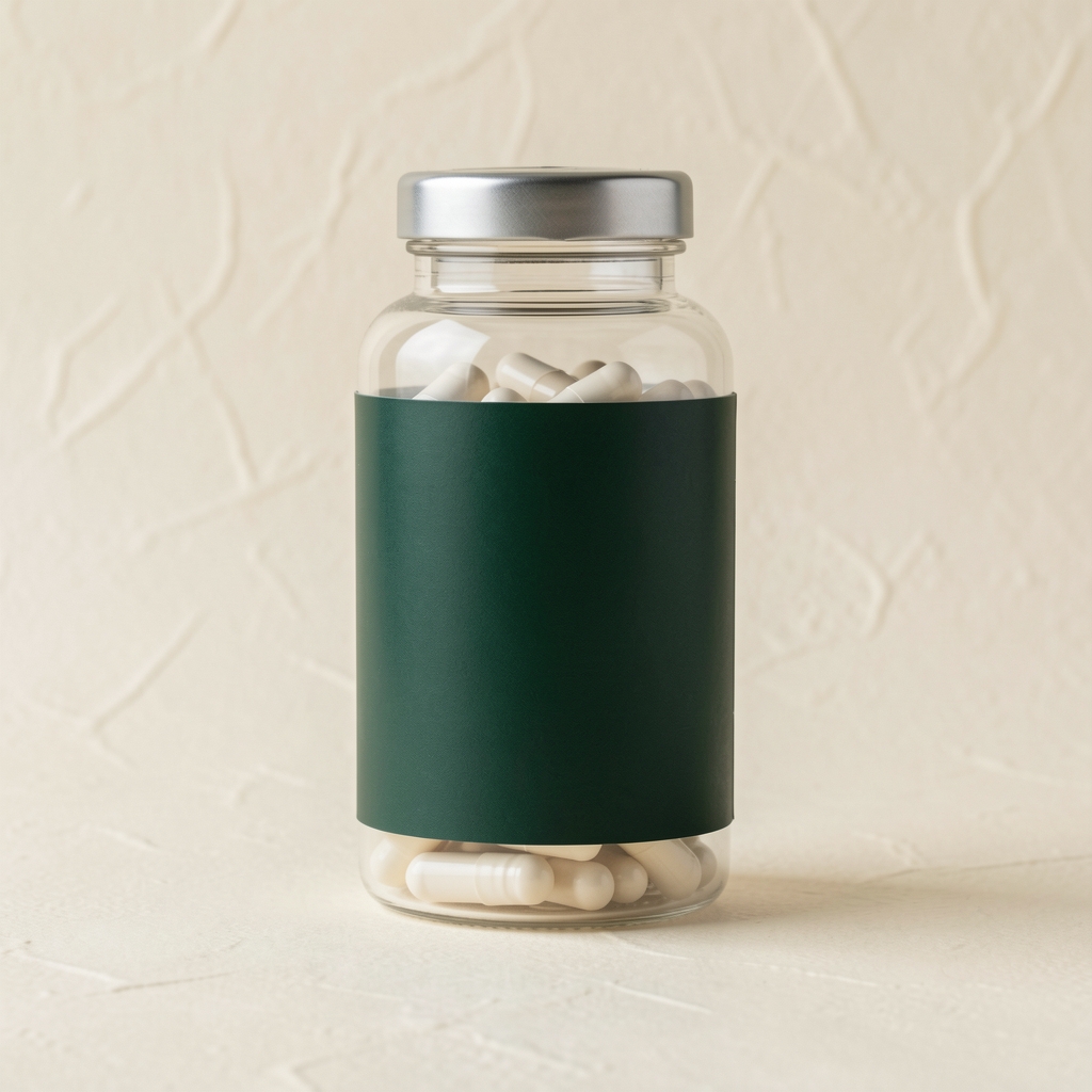 Transparent capsule supplement bottle with dark green label on a pale cream textured background, editorial still life product photography